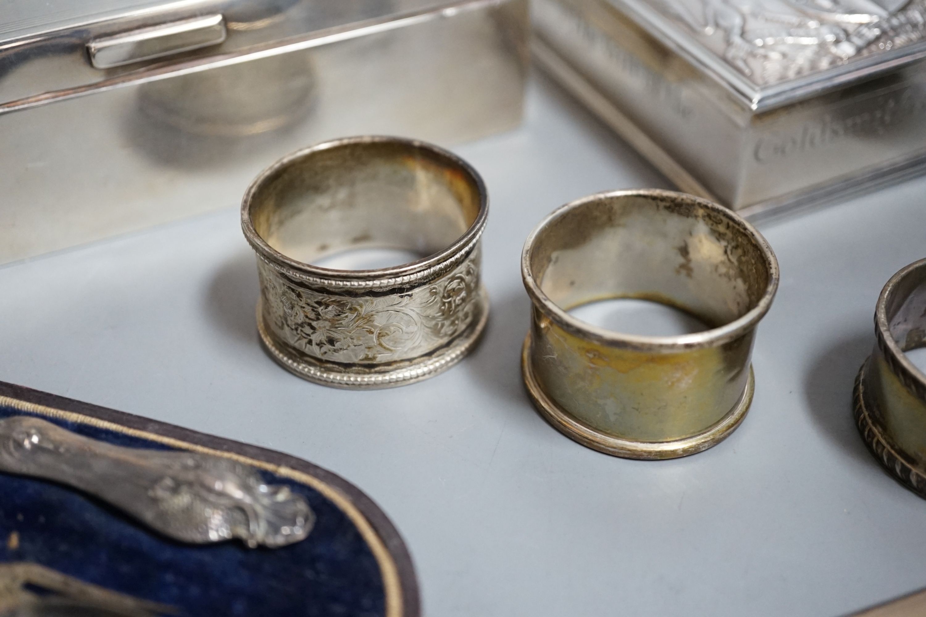 Sundry silver items including a George V 'The Gift of the Goldsmiths Company' box by Garrard & Co, London, 1926, 92mm, a silver cigarette case and box, four silver napkin rings, a cased silver christening trio and a silv